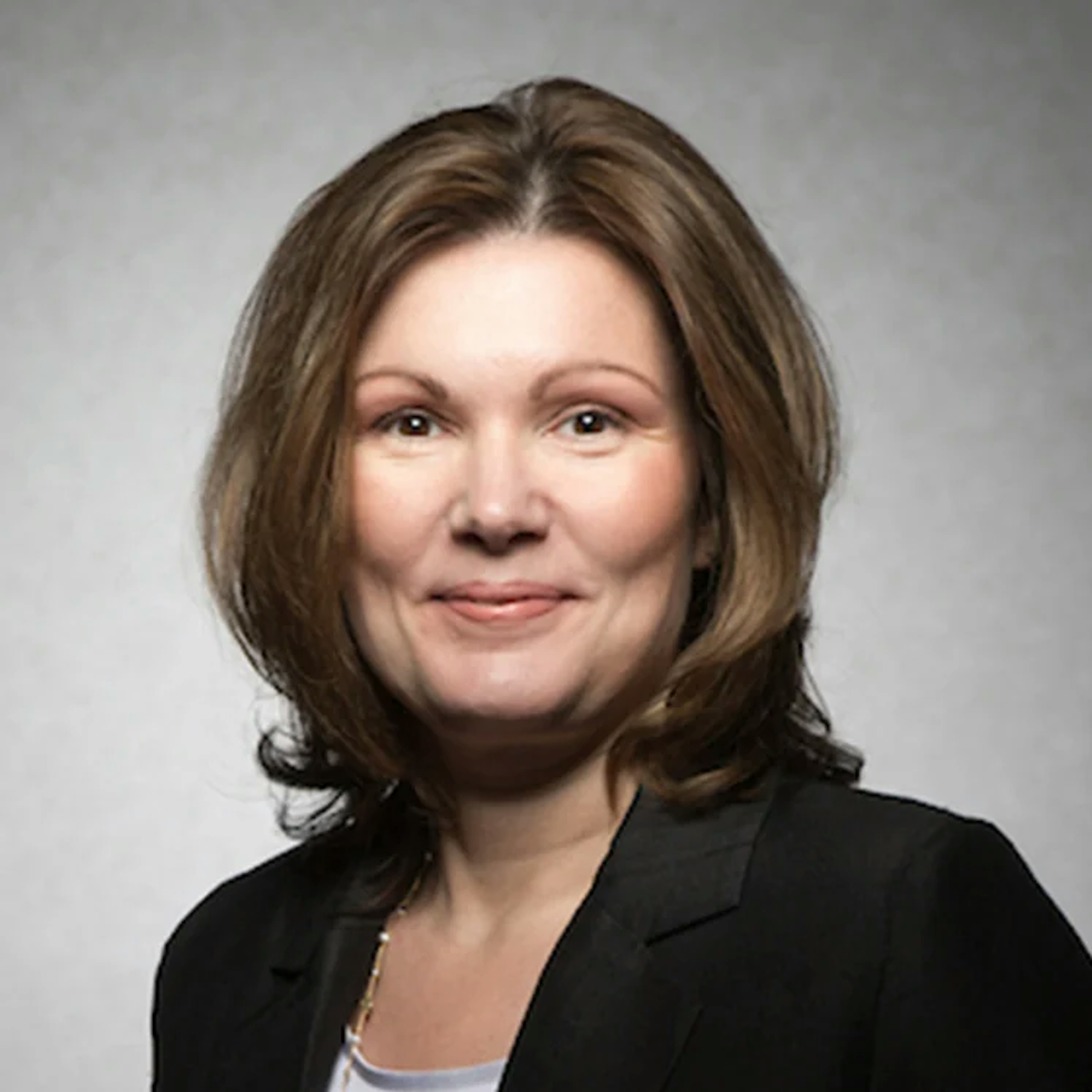Portrait of Karelle Lamouche, a woman with shoulder-length light brown hair, smiling and wearing a black jacket over a black top.