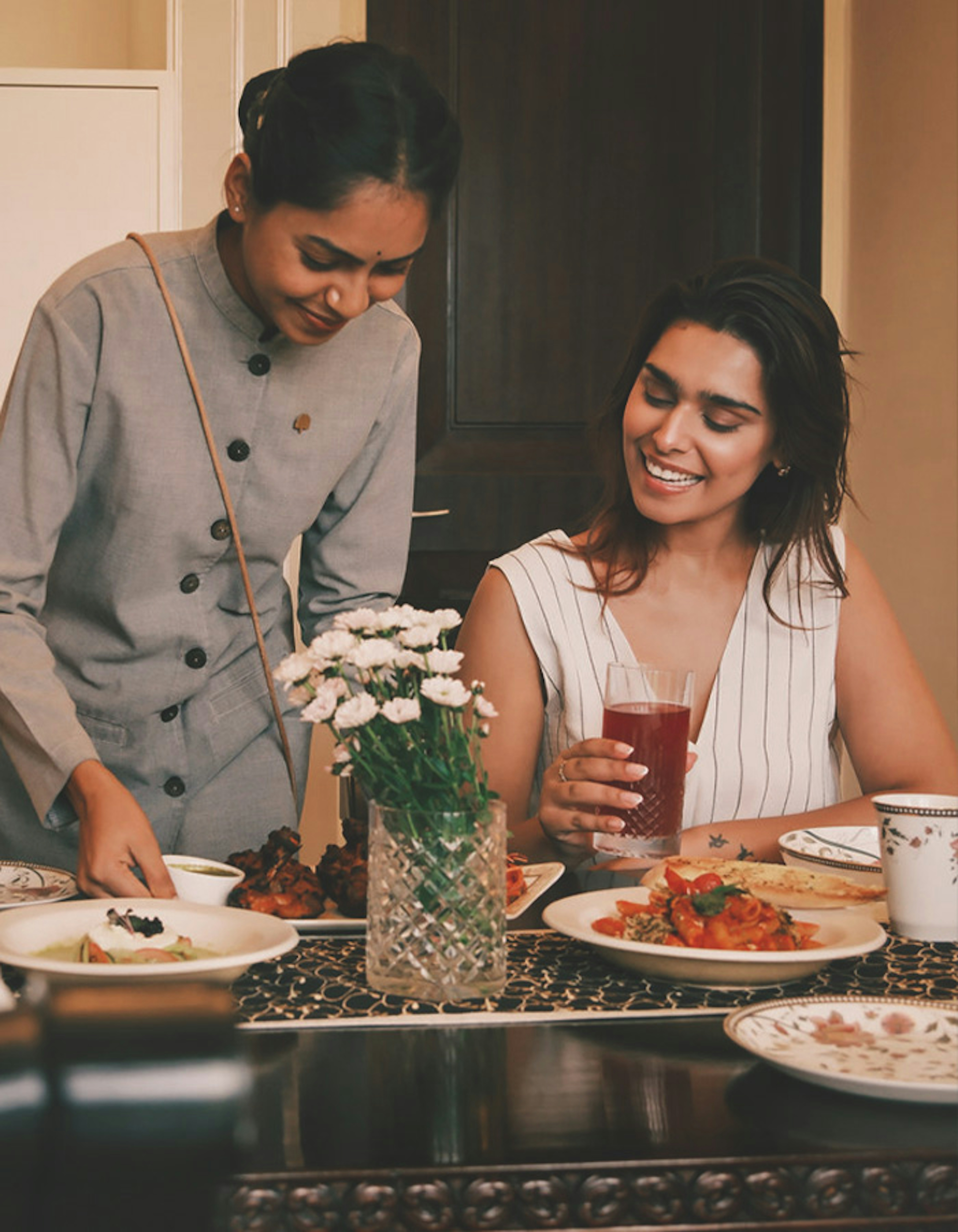 A smiling couple enjoying tea time together, seated at a table with assorted pastries in front of them.