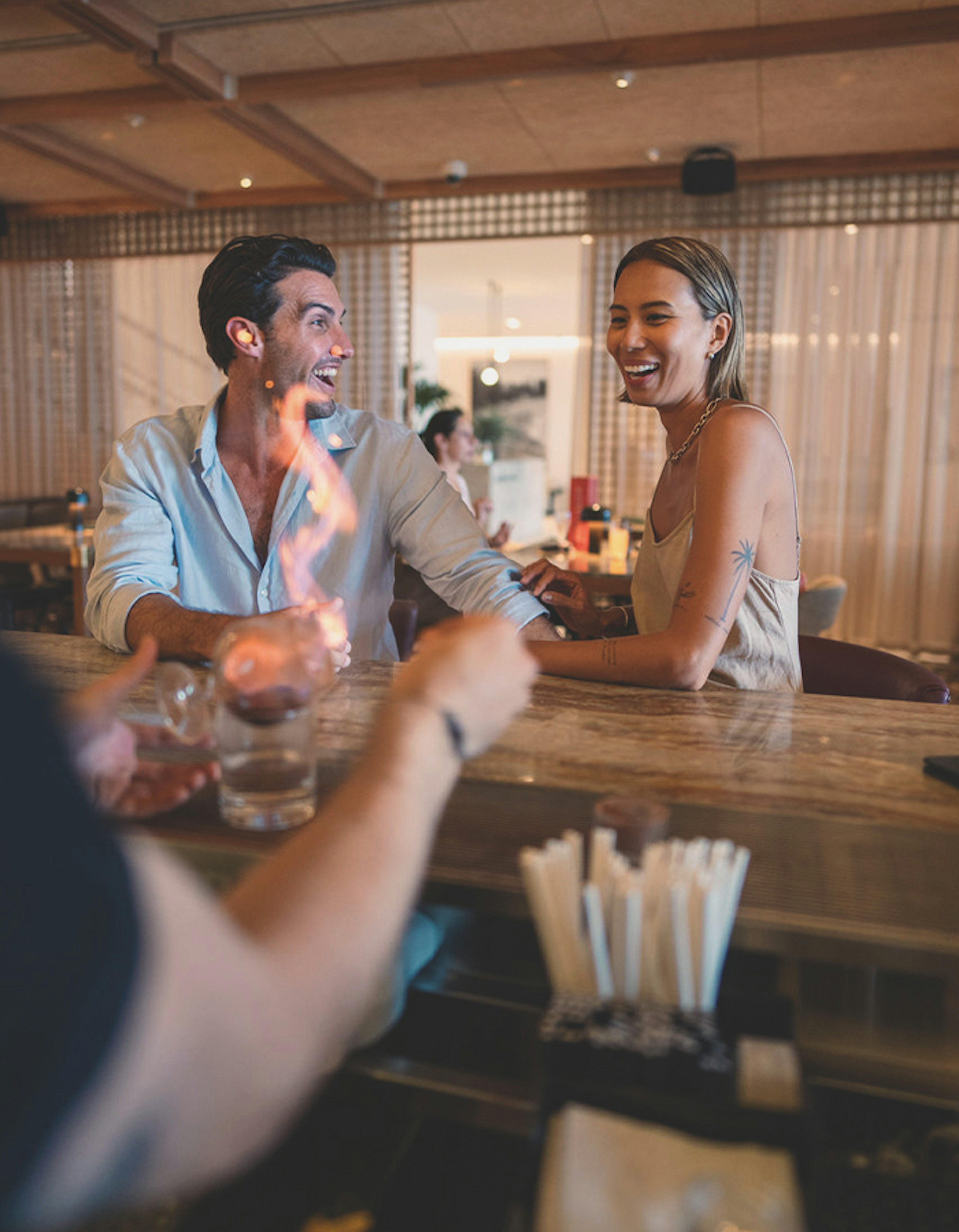 A bartender skillfully preparing a drink in front of two guests seated at the bar.