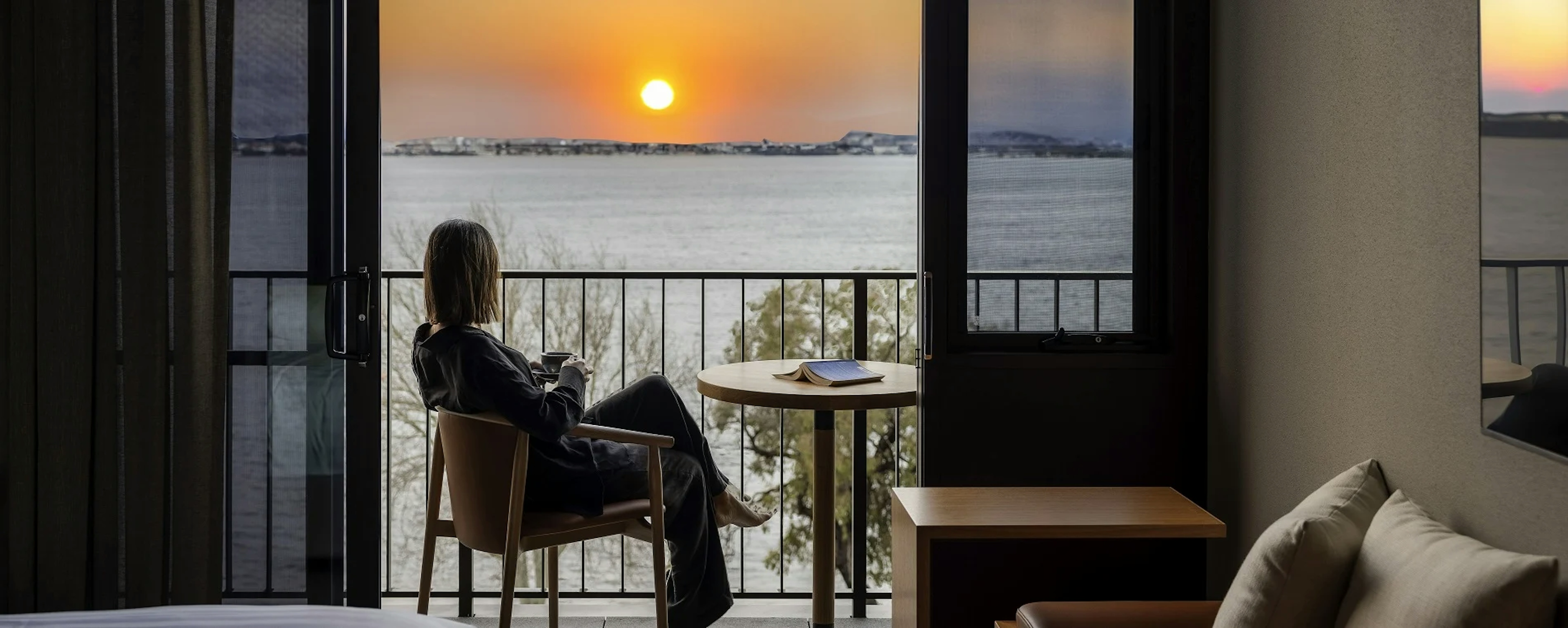 women outside with a book and looking the sunset